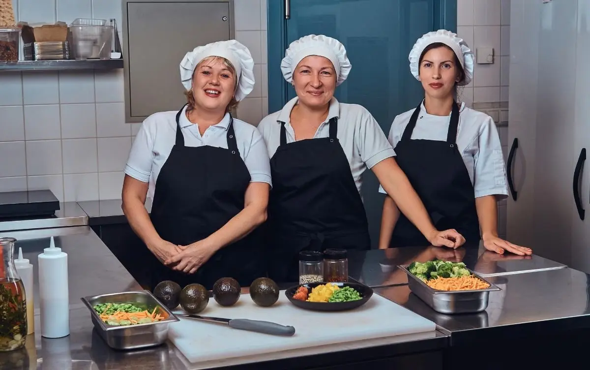 Tres integrantes del equipo de cocina de Valcon Solutions presentando platillos recién preparados